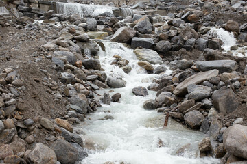 A low-flowing river with banks full of round stones