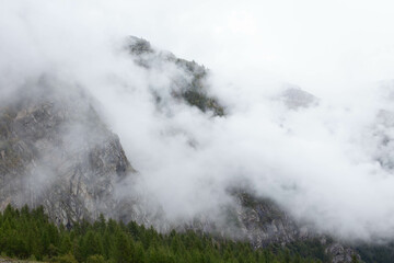 Passing clouds over idyllic landscape in the Alps with snow-capped mountain tops in the background.