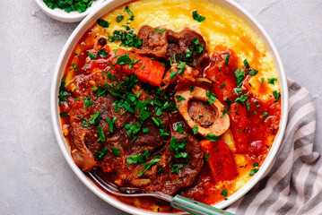 Stewed in osso bucco sauce with vegetables and cheese polenta in a bowl.style huggr