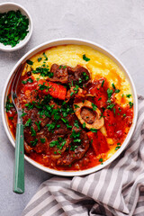 Stewed in osso bucco sauce with vegetables and cheese polenta in a bowl.style huggr