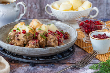 Traditional Swedish meatballs in creamy sauce with boiled potatoes and lingonberries