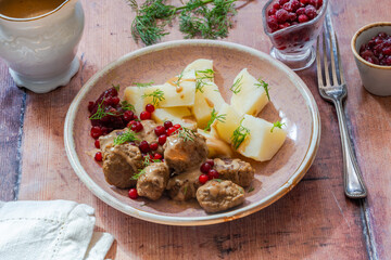 Traditional Swedish meatballs in creamy sauce with boiled potatoes and lingonberries
