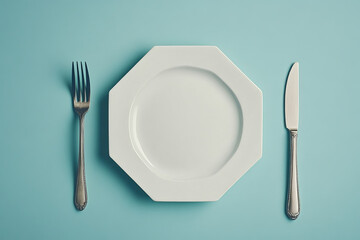 Empty white octagonal plate with fork and knife on a light blue background top view minimalistic style concept of dining table setting and elegant dishware with silver cutlery flat lay arrangement