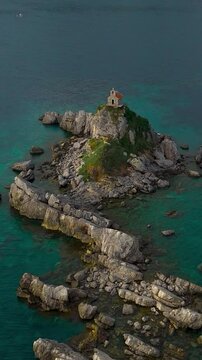 The church on an island-rock rising from the sea is a magical sight, harmoniously integrated into the natural landscape. Petrovac, Montenegro. 4k drone video. Vertical video for reels.