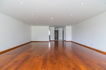 amplia sala de departamento vacio con piso de madera