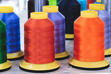 Spool of thread on an industrial sewing machine in a garment factory, industrial textile background, sewing factory, clothing manufacturing