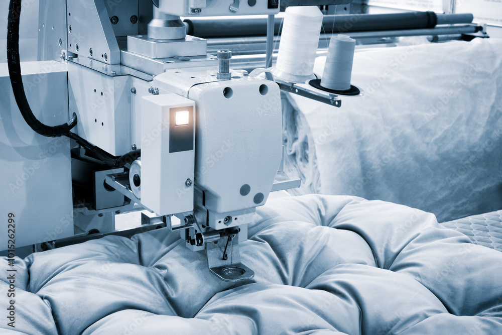 Poster a sewing machine is working on a piece of fabric. the machine is white and has a black and silver de
