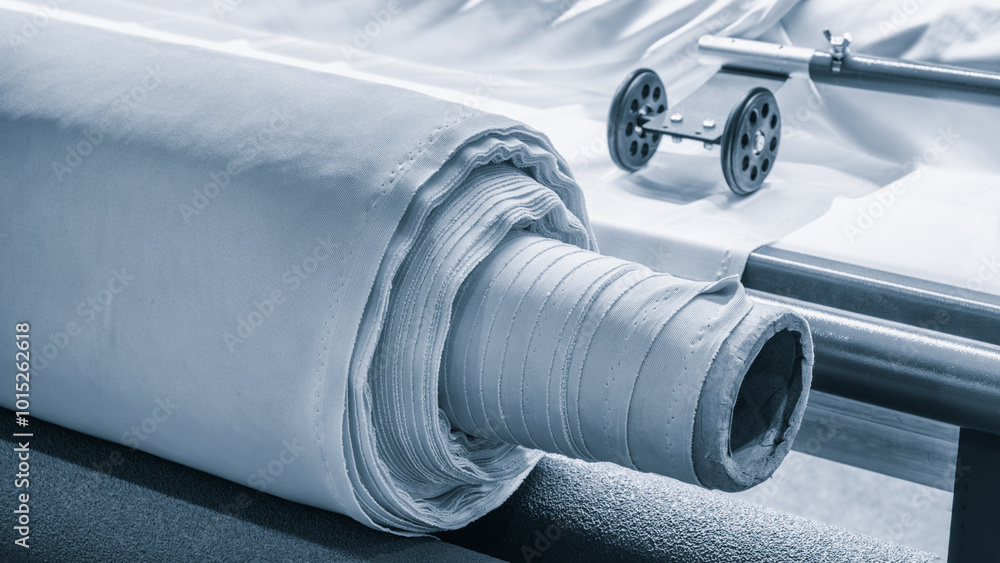 Leinwandbilder a roll of fabric is laid out on a table next to a sewing machine. the machine is likely used to cut 