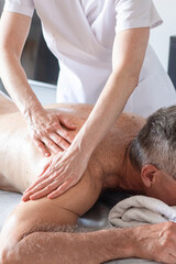 Man receiving back massage from masseur in spa