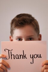 Teenager boy holding a white card with the words "thank you" © Gosia