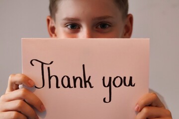 Teenager boy holding a white card with the words "thank you"