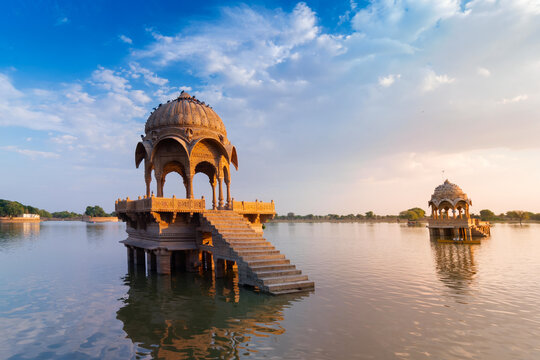 Beautiful Chhatris, dome-shaped pavilions on Gadisar lake or Gadaria lake, an artificial lake once only water source of Jaisalmer city. Blue sky , reflections on water. Jaisalmer, Rajasthan, India.