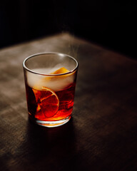 Coctel naranja con humo sobre una mesa de madera
