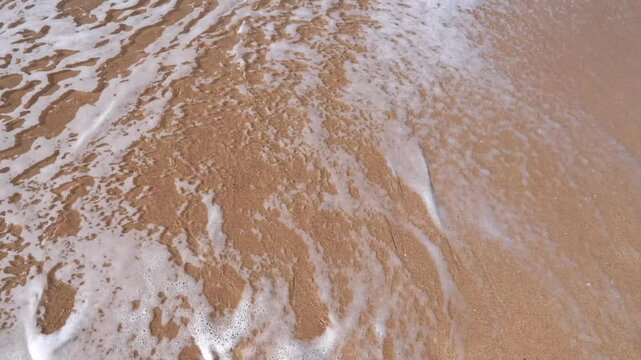 Ocean waves washing away 2024 written in sand