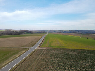 View from above of a landscape with farm fields and a long road in spring