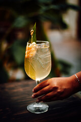 Mano tomando un coctel en copa elaborado por un mixologo/bartender