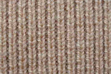 Fototapeta premium texture of knitted light brown sweater, close-up texture of beige knitted fabric, macro texture of tan knitted woolen clothes