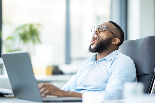 Cansado ap&oacute;s um longo dia de trabalho, o homem boceja em sua mesa no escrit&oacute;rio