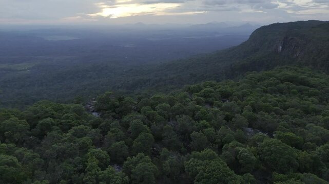 Drone flies into sunset over Pedra M&atilde;o de Deus and the surrounding valley in Tepequem, Roraima, Brazil