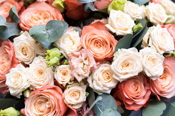 A bouquet of orange roses, pink and green lisianthus, and eucalyptus branches. Close up