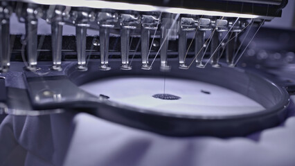 Obraz premium Close up of industrial loom creating embroidery on white fabric. Media. Professional equipment details.