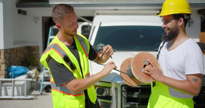Two construction workers are engaged in a conversation about the various materials needed for a house remodeling project. One worker is wearing a protective helmet while the other dons a safety vest