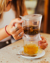 Plano detallde de una mano filtrando una Tisana herbal
