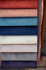 A vertical arrangement of fabric swatches in vibrant colors and textured surfaces, offering a variety of materials for design and upholstery.
