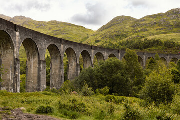 Obraz premium Famous Glenfinnan Viaduct and Jacobite Steam Train in the Picturesque Scottish Highlands