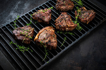 Authentic barbecued T-Bone lamb steak with thyme served as close-up on a rustic grillage