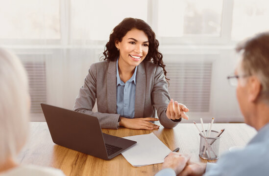 Expert. Senior couple sitting together at the desk and listening to their mexican financial advisor gesturing