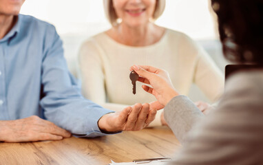 Real Estate Consultant Giving Key Of New House To Happy Elderly Couple, Selective Focus