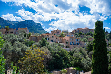 Obraz premium Deia, Mallorca cityscape with Serra de Tramuntana mountain landscape in the background, tree in front, majorca spain