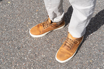 close-up shot featuring stylish pair brown sneakers adorned by man's legs in light gray trousers,...