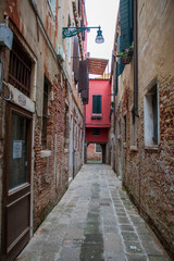 Fototapeta premium narrow street in the old town in Venice, Italy with red house 
