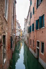 narrow street in Venice with a canal and colored old houses