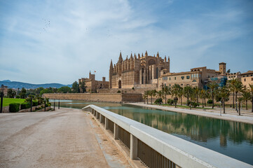 Cathedral of Santa Maria of Palma La Seu in Palma de Mallorca with lake and park, with path and fence in front, majorca