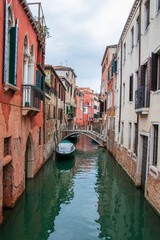 Scenic Venetian canal with traditional buildings and stone bridge. Beautiful Venice canal with colorful historic buildings, arched stone bridge, and calm water reflecting the scene.