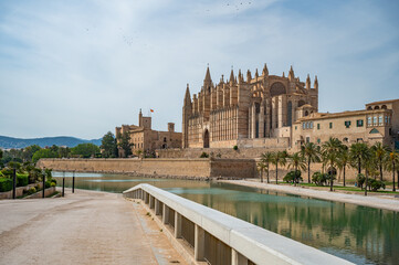 Cathedral of Santa Maria of Palma La Seu in Palma de Mallorca with lake and park, with path and fence in front, majorca