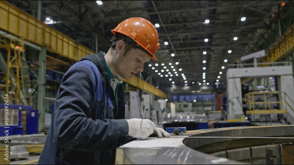Poster worker at factory makes measurements of structure. stock clip. worker in hard hat measures parts of 