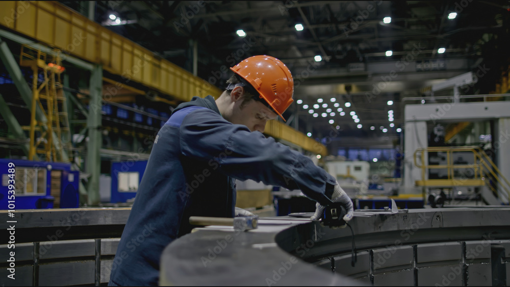 Poster worker at factory makes measurements of structure. stock clip. worker in hard hat measures parts of 