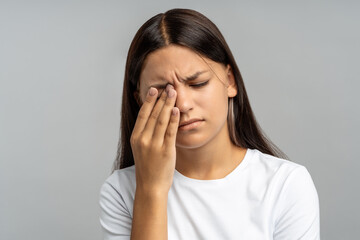 Exhausted, distressed teenage girl rubs eyes, suffering from burnout, fatigue and sleep deprivation...