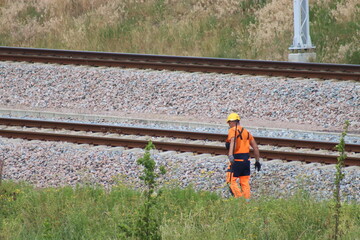 A worker in a yellow road service helmet is repairing railway tracks