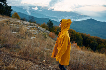 A solitary figure in a vibrant yellow raincoat standing atop a hill, gazing over a serene valley Nature, exploration, solitude and contemplation