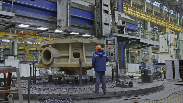 Worker with remote control and rotating lathe. Stock clip. Worker with control panel for factory metalworking machines. Turning carousel machine for metalworking - Powered by Adobe