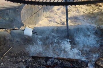 Marshmallows baked over a large fire. A metal grate with white marshmallows on it.