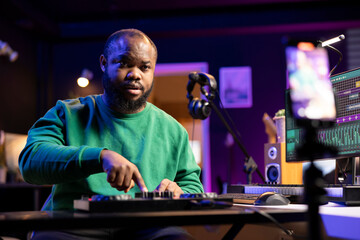 Music producer hosting an online master class lesson to teach controls and buttons on a stereo console, explains editing in post production. Confident musician hosting a mix and master course.