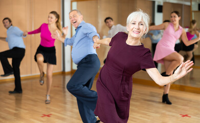Obraz premium Spirited old pair training Latino dance during workout session. Pairs training ballroom dance in hall