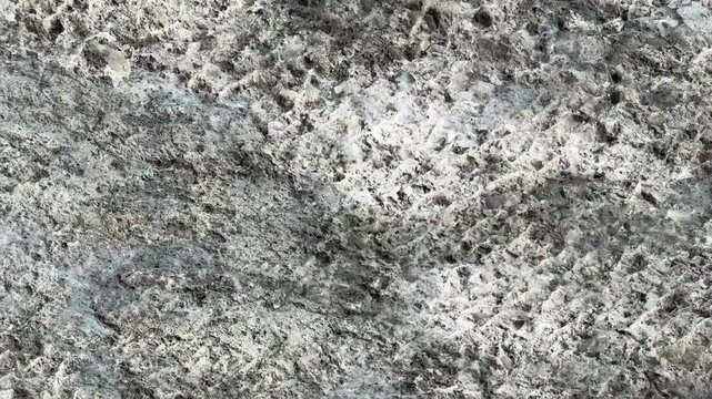 Reflection of glare from water on gray stone texture close-up. Macro photography of the stone. natural mineral background. High-quality 4k footage