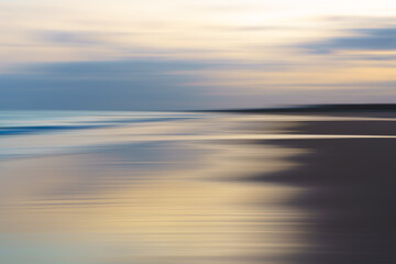 Abstract motion blur of ocean waves and sky in soft, muted tones.